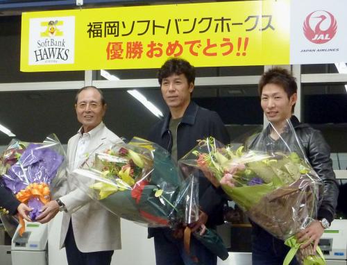 優勝旅行出発前に、航空会社スタッフから贈呈された花束を手に笑顔を見せるソフトバンクの（左から）王球団会長、秋山監督、本多選手会長