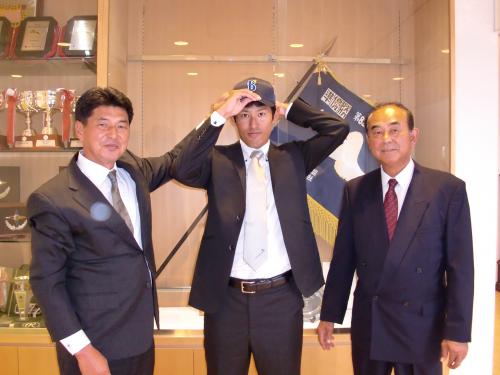 ＤｅＮＡドラフト３位のＮＴＴ東日本・井納（中央）は、あいさつに訪れた吉田編成・スカウト部長（右）、担当の武居スカウトから渡されたＤｅＮＡの帽子をかぶる