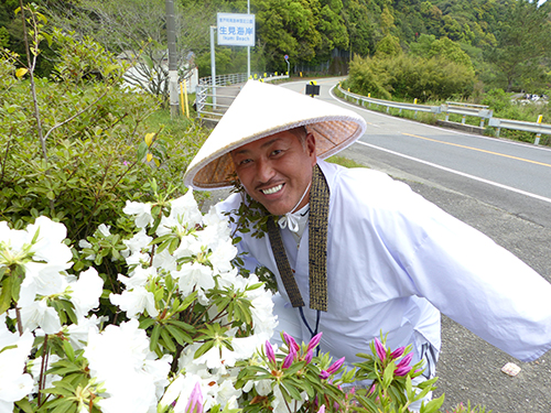 お遍路を歩く清原氏はツツジの花を見て笑顔を見せる