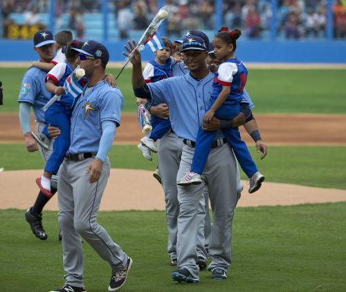 親善試合を前に、キューバ代表のユニホームを着た子供を抱いて、観客の声援に応えるレイズの選手（ＡＰ）
