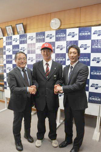 カープの赤い帽子をかぶり、笑顔で指名挨拶を受けた広島ドラフト２位の花咲徳栄・高橋昂也。左は苑田スカウト統括部長、右は担当の尾形スカウト
