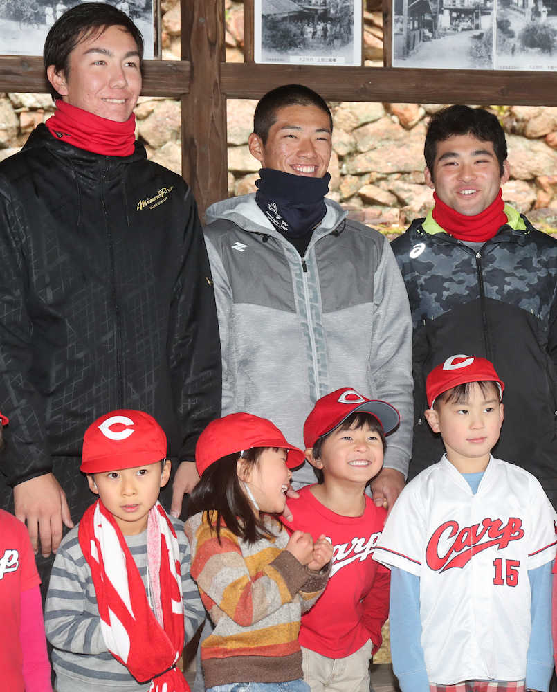カープのユニホームを着た子供たちと笑顔で記念撮影をする中村奨（中央）