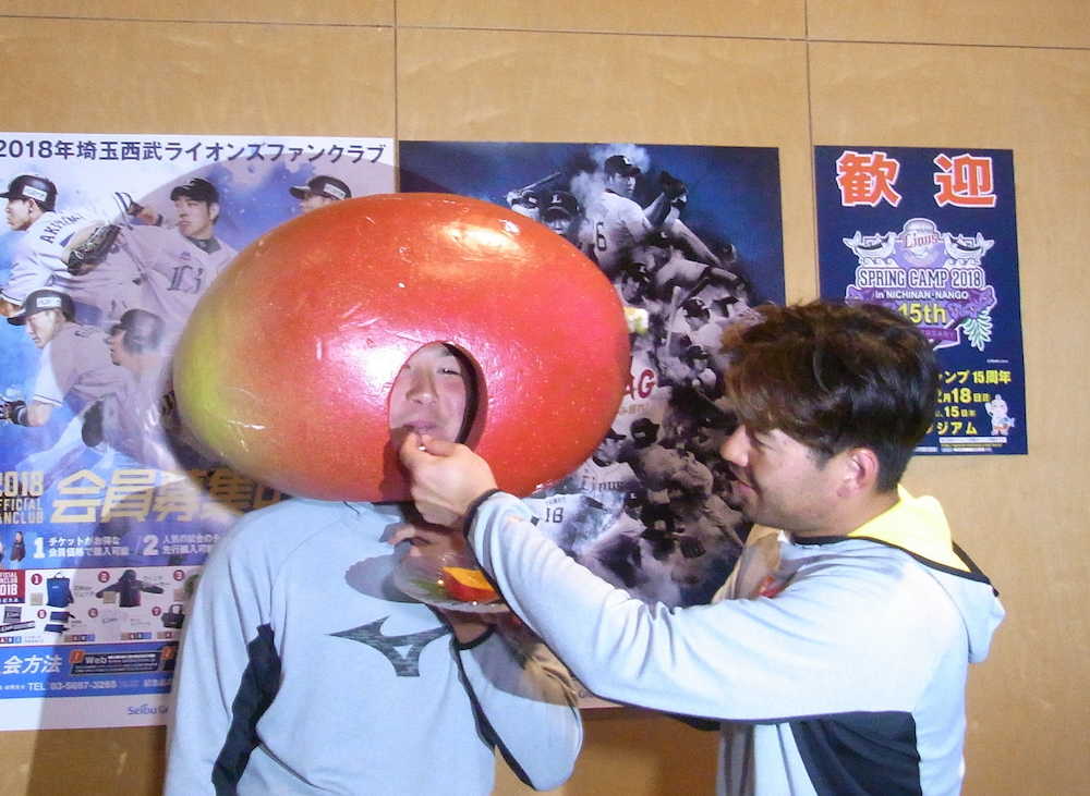 マンゴーのかぶりものをした西武・中塚（左）は炭谷からマンゴースイーツを食べさせてもらう