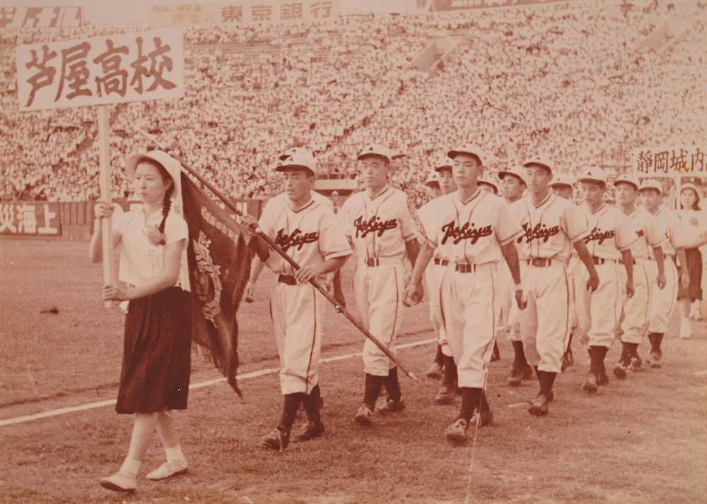 １９４９年夏の甲子園大会開会式で入場行進する芦屋高ナイン。先頭で旗を持つ有本義明さん。市西宮高のプラカード嬢が初めて登場した大会だった（有本氏提供）