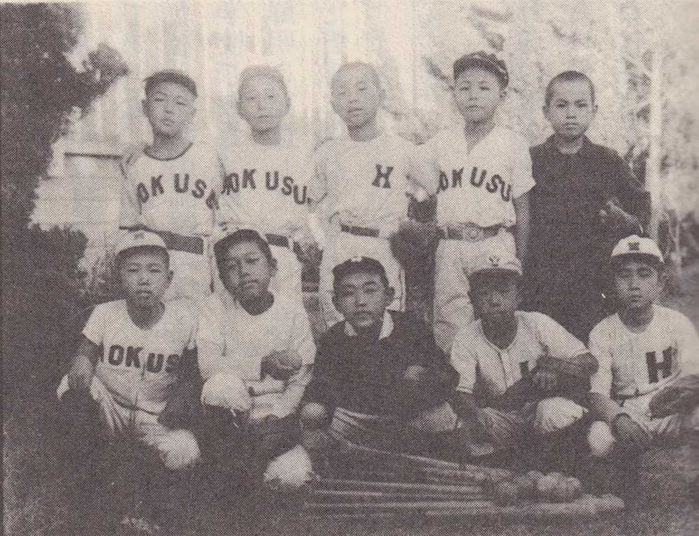 野球少年だった佐山和夫さん（前列中央）。１９５１年、転校先の和歌山県有田郡・湯浅小学校６年生当時。ユニホームの「ＨＯＫＵＳＵ」は「ＨＡＷＫＳ」のつもりだった（佐山さん提供）
