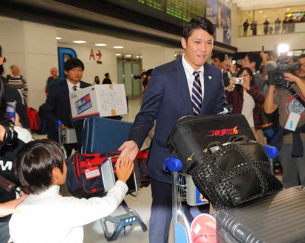 成田空港に到着した坂本勇は出迎えたファンのハイタッチに応える（撮影・島崎忠彦）
