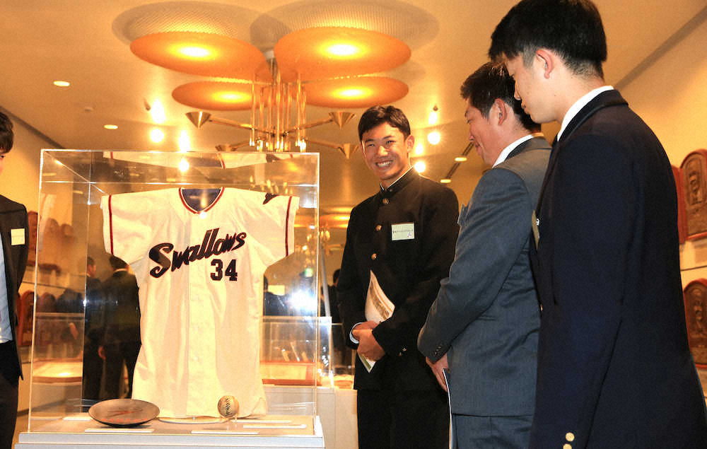 展示された故・金田正一氏のユニホームに笑顔を見せる奥川（左）らヤクルトの新人選手たち