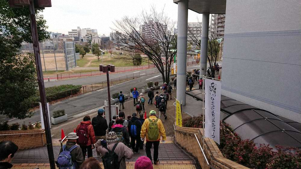「1.17ひょうごメモリアルウォーク2020」で神戸常盤アリーナを出発する人びと。左は神戸市民球場跡にできた西代蓮池公園（17日午前8時30分、神戸市長田区）