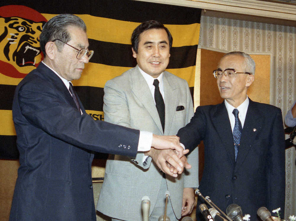 1987年10月16日、就任会見で久万オーナー（左）と岡崎社長（右）と手を合わせる村山新監督