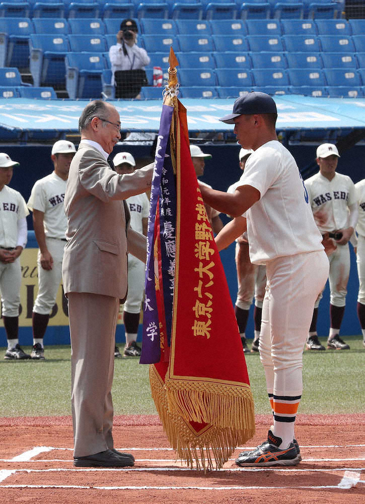 春季リーグ閉会式で、東京六大学野球連盟・井上理事長（左）から優勝旗を授与される法大・羽根（撮影・郡司　修）