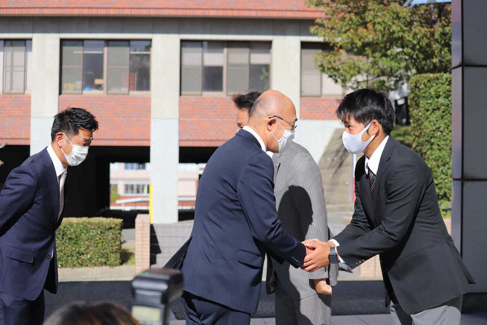 指名あいさつに訪れた阪神・畑山統括スカウトと握手を交わす、九産大・岩田将貴投手