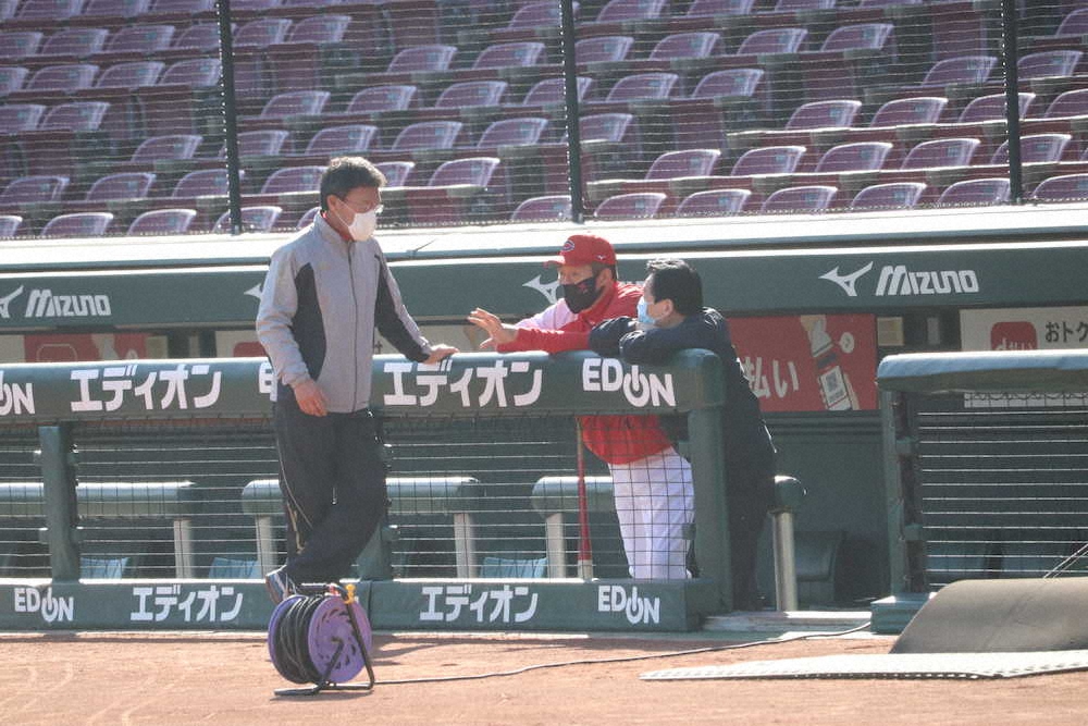 秋季練習を見つめながら一塁ベンチで話し合う（左から）河田ヘッドコーチ、佐々岡監督、鈴木球団本部長