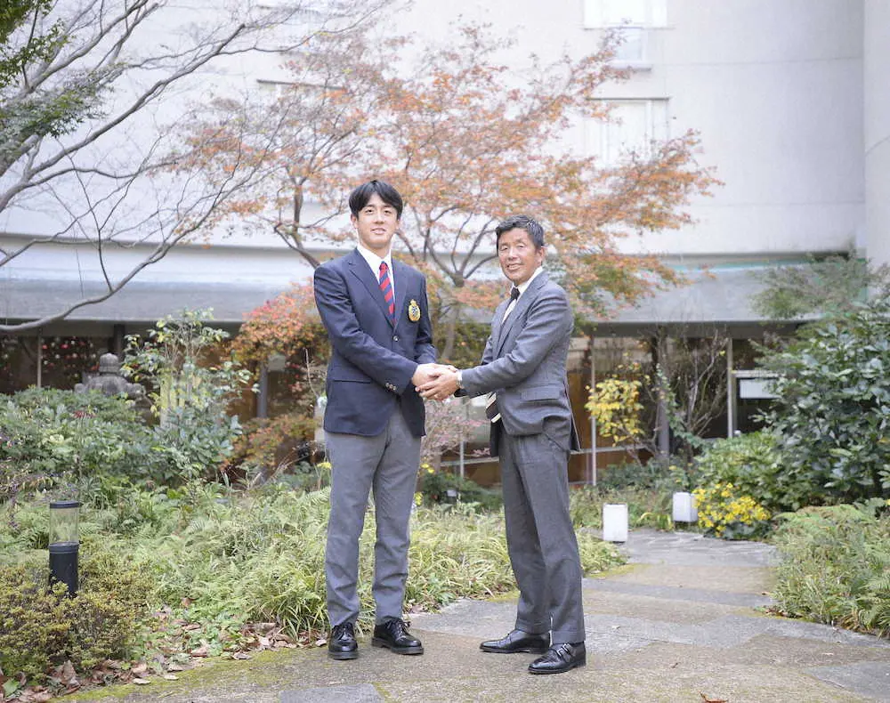 仮契約を交わし、ホテルの中庭で熊崎誠也スカウト（右）と握手する日本ハム8位指名の北山亘基