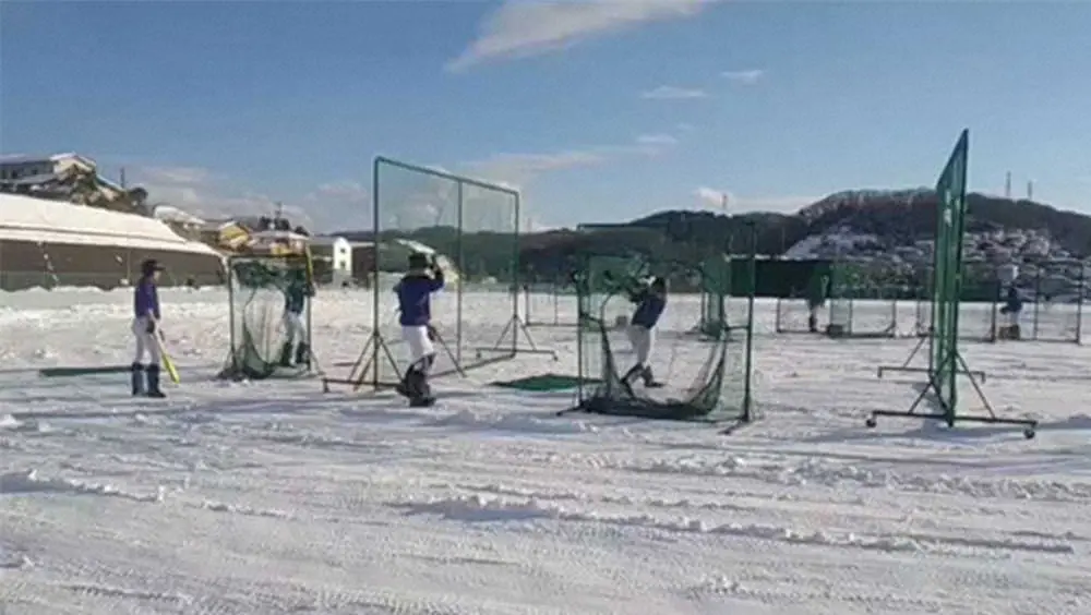 雪の残るグラウンドで打撃練習する星稜ナイン