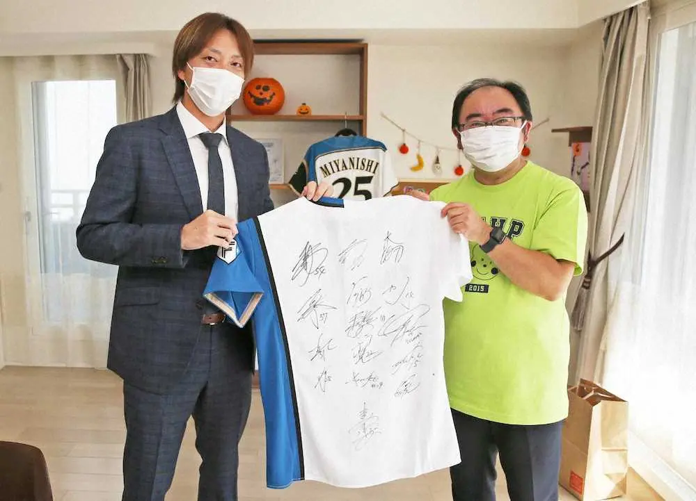 北海道こどもホスピスプロジェクトの佐藤代表（右）にサイン入りユニホームを手渡す日本ハム・宮西（代表撮影）