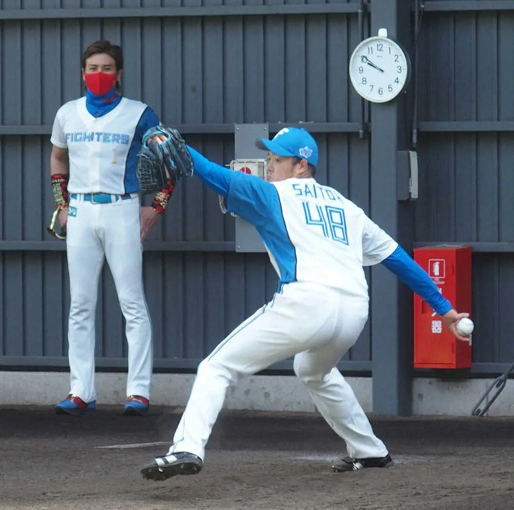 新庄監督（左）が見守る前でブルペン投球を行う日本ハム・斎藤