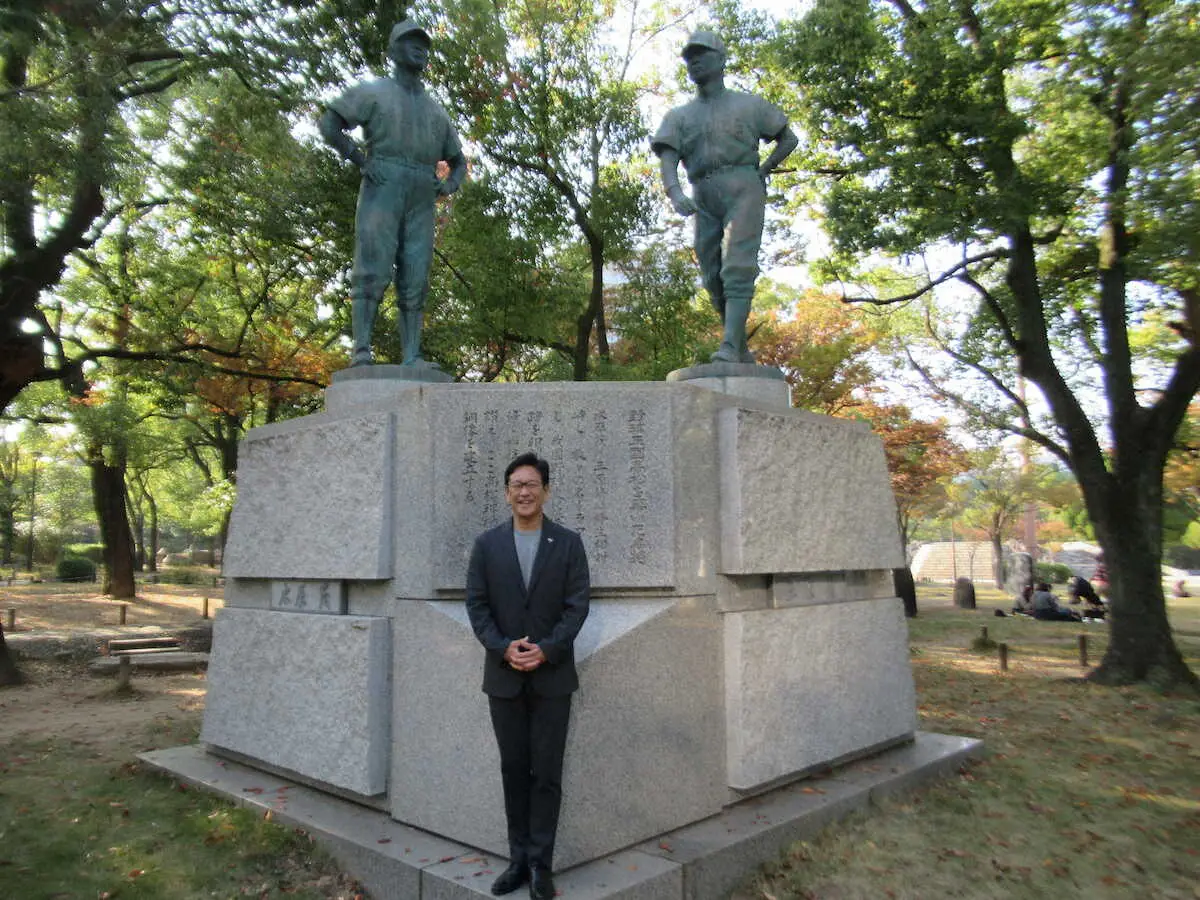 三原氏（右）と水原氏（左）の銅像の前に立つ栗山氏　　　　　　　　　　　　　　　　　　　　　　　　　　　　　　　