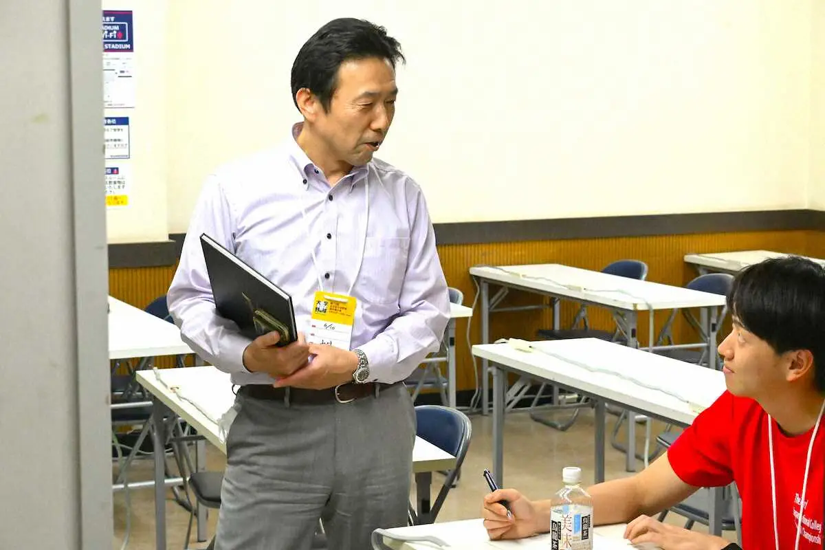 開幕戦を終えた記録員にアドバイスする日本野球協議会オペレーション委員会記録部会の山川誠二氏（左）