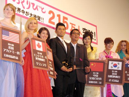 各国の美女に囲まれ、笑顔の本木雅弘（中央・左）と滝田洋二郎監督