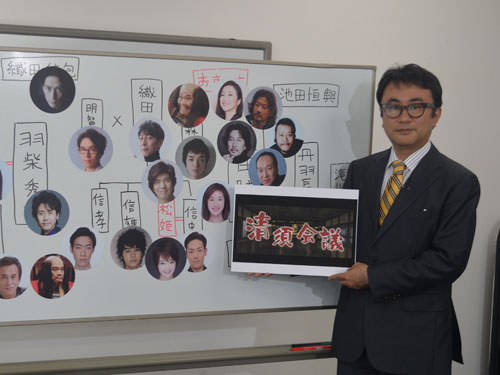 「清須会議」のロゴを持つ三谷幸喜監督。登場人物と役者の相関図を自らホワイトボードに描いて説明