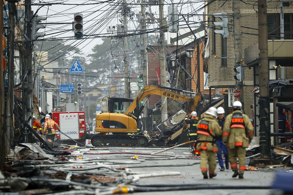 ２０１６年１２月、大火から一夜明けた糸魚川市中心部の現場周辺で作業する消防関係者