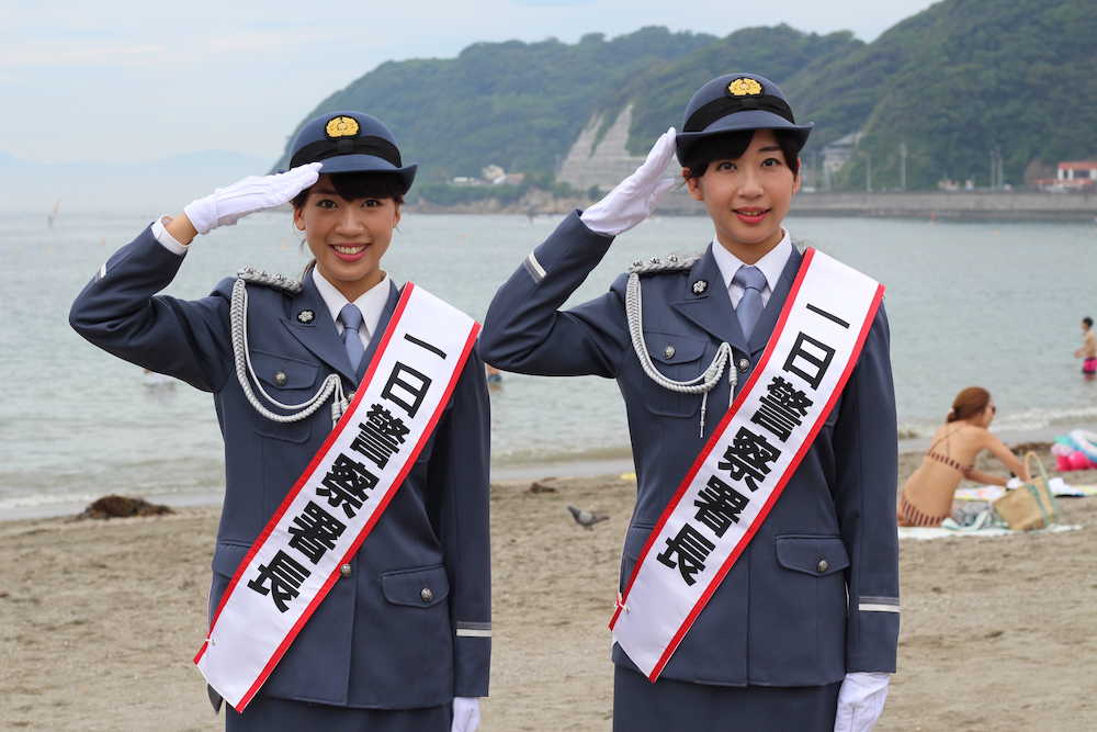 逗子海岸をバックに制服姿で敬礼する山田姉妹の麗（左）と華