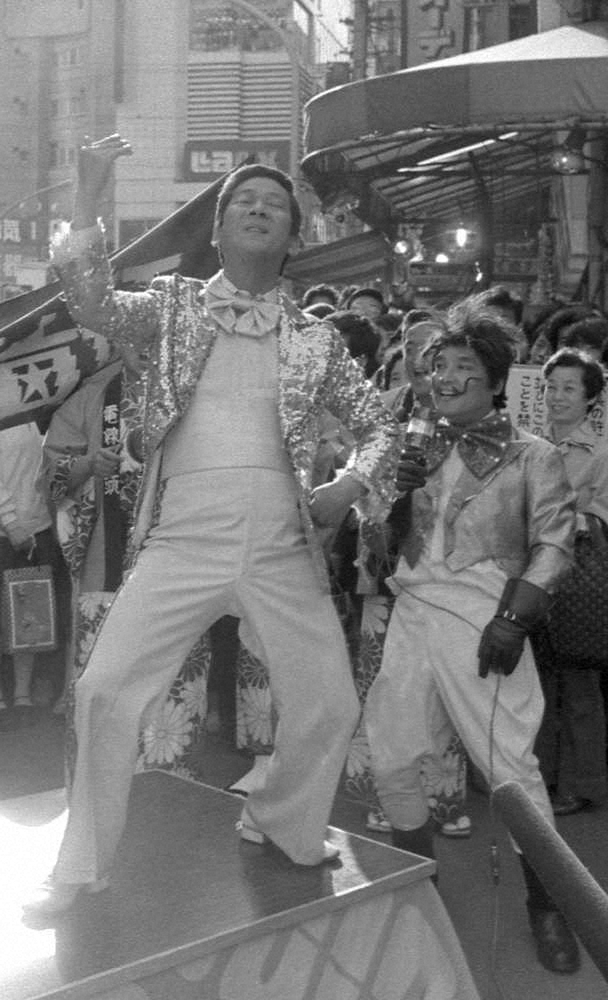 77年、秋葉原・電気街の路上にすえられた電気ゴタツの上で「電線音頭」を踊る小松政夫さん（左）と伊東四朗