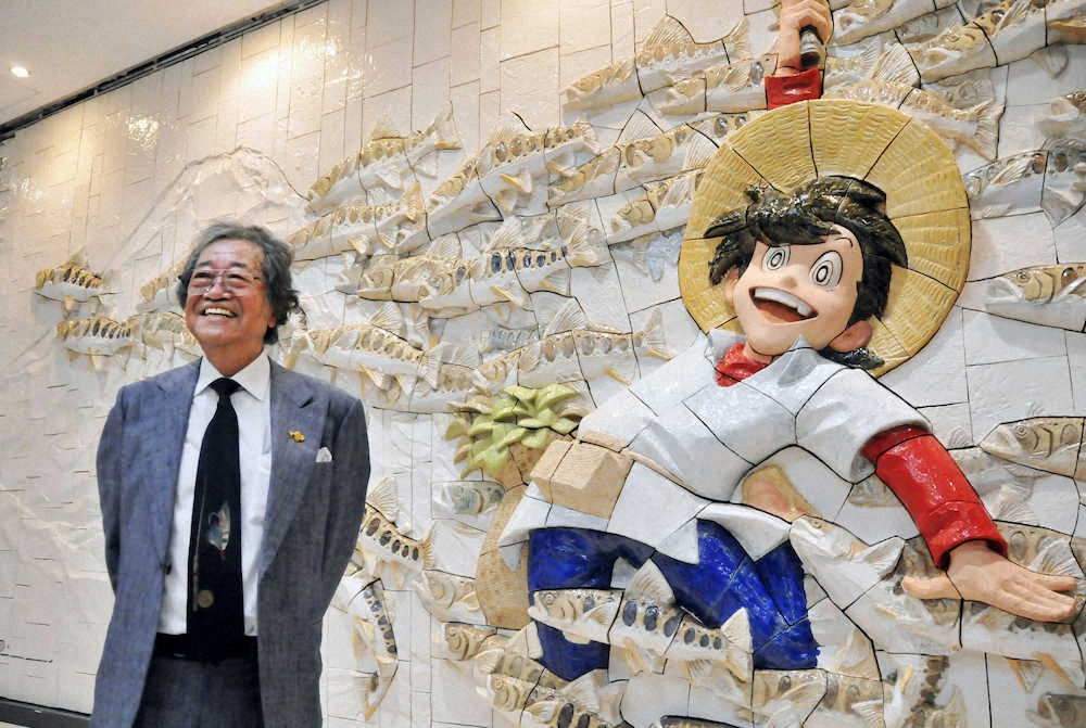 16年10月、秋田空港の「釣りキチ三平」のレリーフの前で笑顔の矢口高雄さん