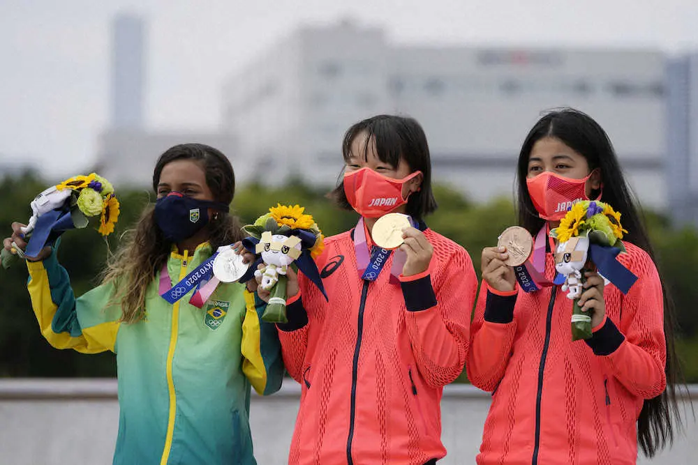 スケードボード女子ストリートのメダル授与式に臨んだ（左から）銀メダルのライッサ・レアウ、金メダルの西矢椛、銅メダルの中山楓奈。中継では背景のビルに「ホウスイ」の文字が映っていた（AP）