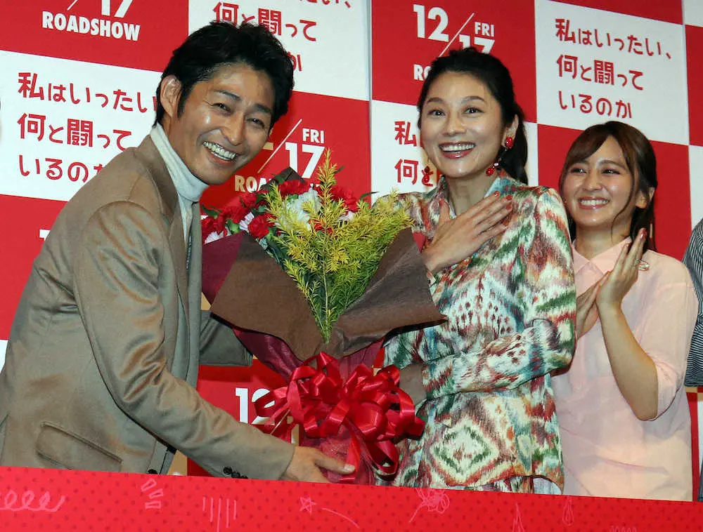 映画「私はいったい、何と闘っているのか」のプレミア試写会で、妻役の小池栄子（中央）に誕生日の花束を贈る安田顕（左）、右は岡田結実