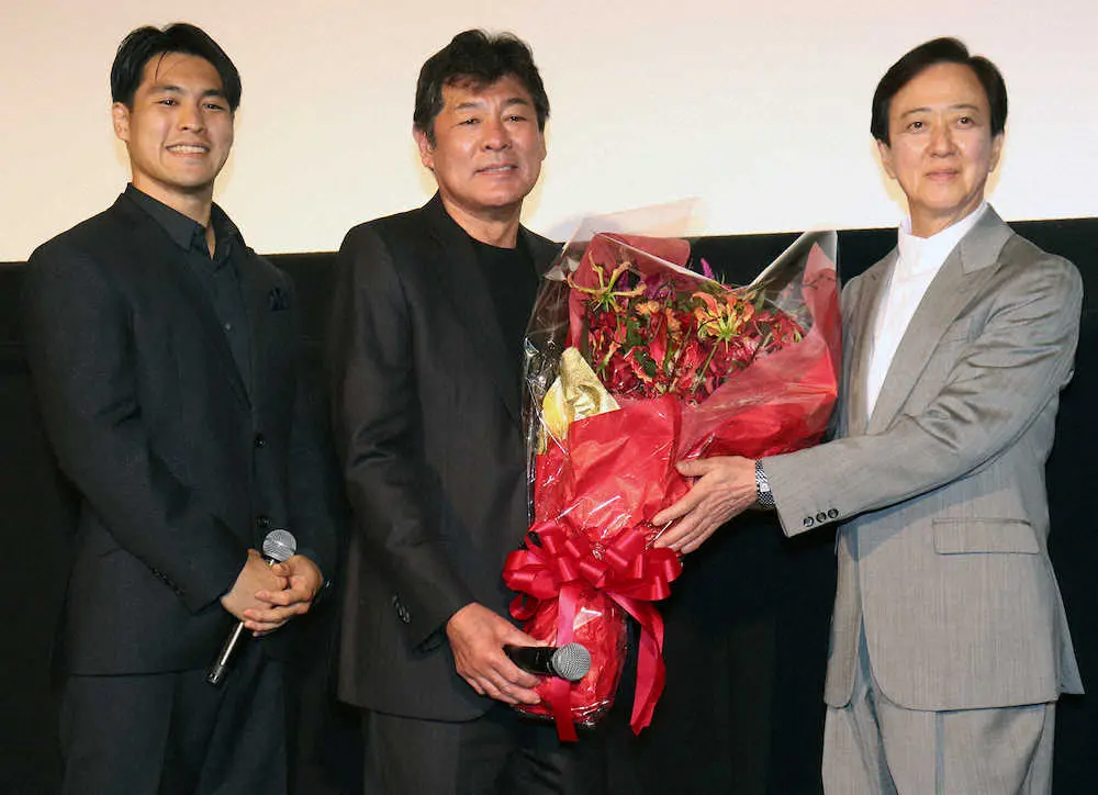 映画「AKAI」の公開記念舞台あいさつに駆け付けた坂東玉三郎（右）に花束を贈られ笑顔の赤井英和（中央）。左は長男の赤井英五郎監督