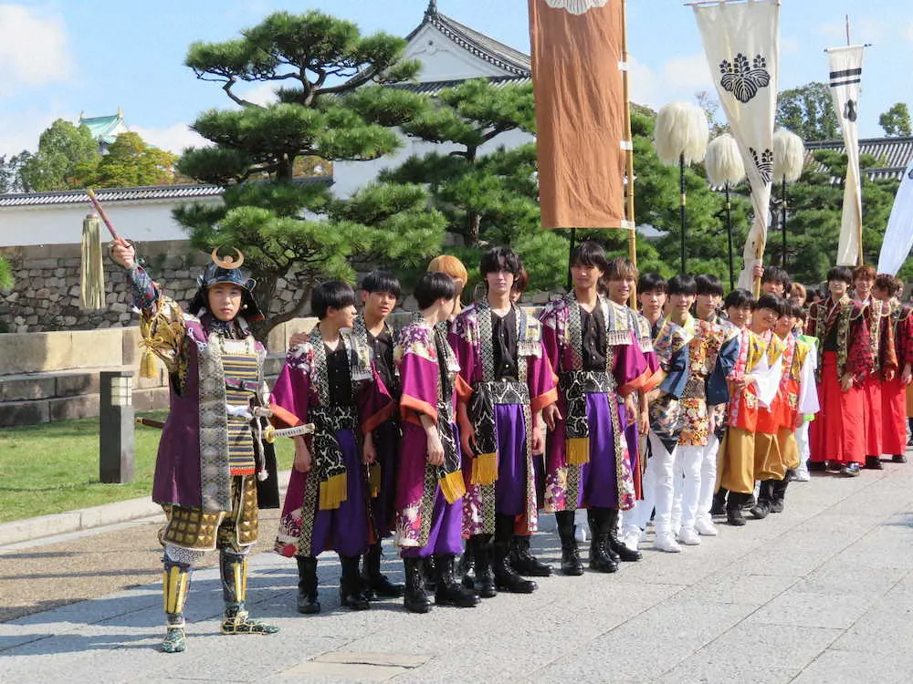 甲冑姿で大阪城の天守閣に向かい大名行列を率いる村上信五（左）　