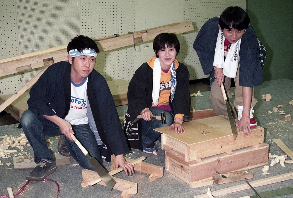 1997年、「天うらら」への出演が決まった猿岩石の森脇和成（左）と有吉弘行（右）は、ヒロインの須藤理彩を囲んで、さっそく大工の作業の特訓を受ける