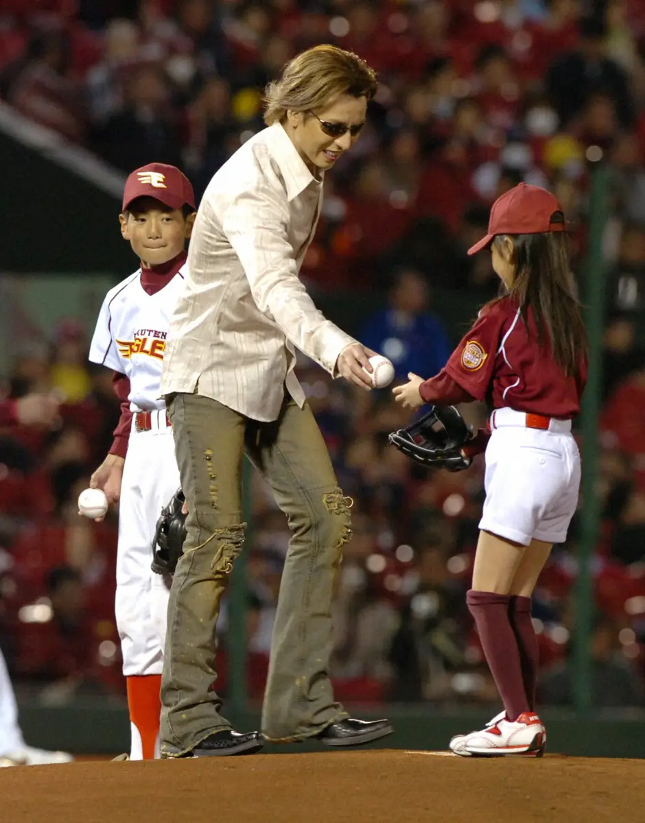 オープニングセレモニーに登場し、始球式を行う子供に笑顔でボールを渡すミュージシャンのYOSHIKI（2005年撮影）