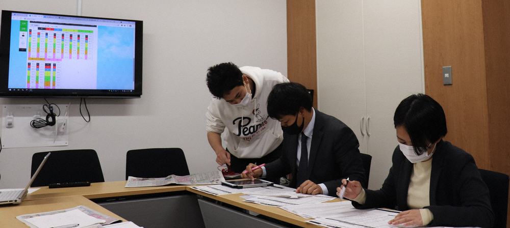 SPAT4で馬券を購入する柳内記者（中央）、指導する藤田記者（左）とレース予想をする小田切記者