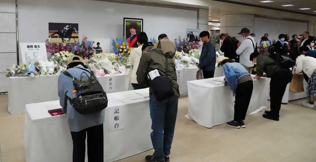 中山競馬場に設置された藤岡康太さんを悼む献花台で合掌する人々（撮影・郡司　修）