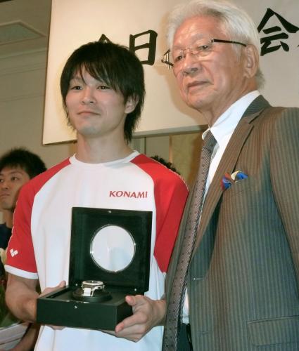 日本体操協会の二木英徳会長（右）から、スイス製高級腕時計を贈られた内村航平