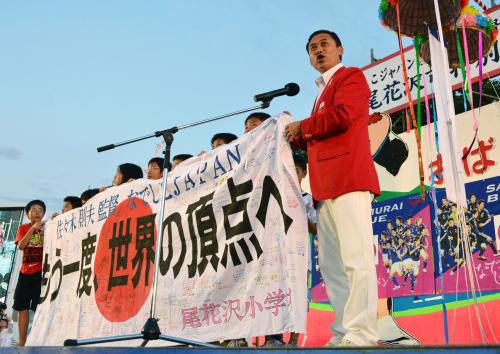 「なでしこジャパン」選手のサイン入り応援横断幕を、制作した小学生たちと広げる佐々木則夫監督