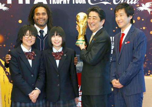 サッカーＷ杯のトロフィーを手に笑顔の安倍首相（右から２人目）右は元日本代表の中山雅史氏