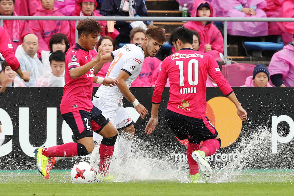 ＜Ｃ大阪・大宮＞前半、大雨の影響で水しぶきをあげながら懸命にボールを追う宇山口（右）と松田（左）