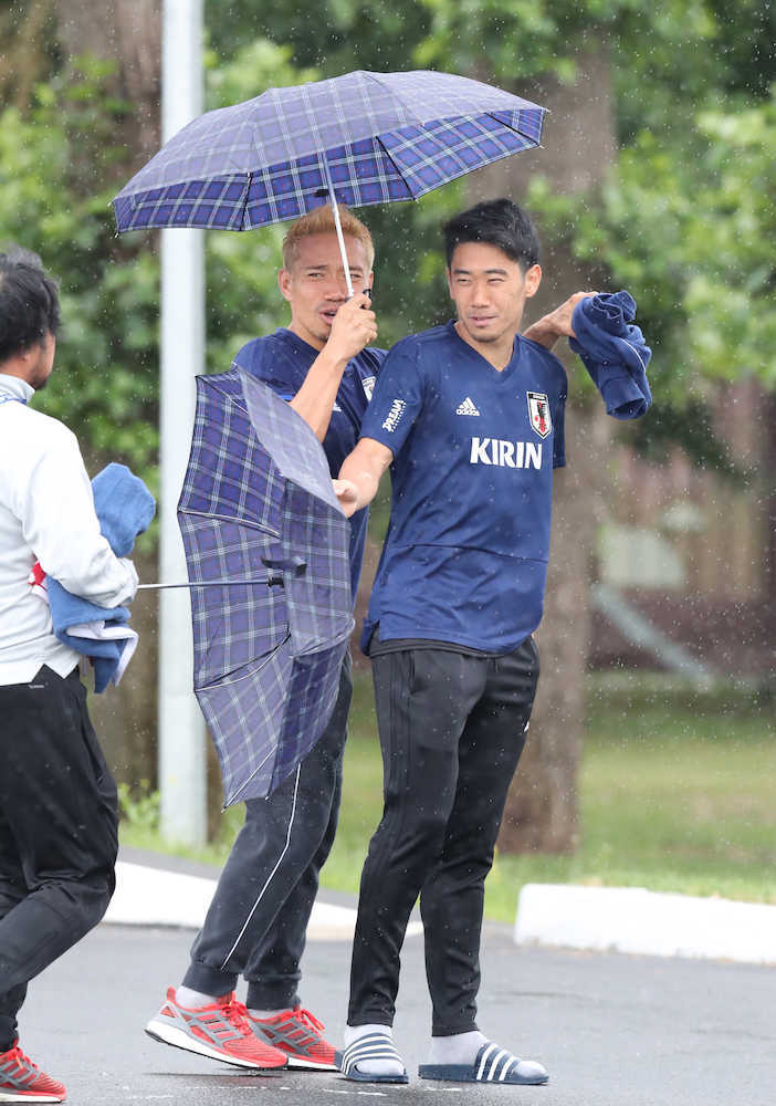 ＜日本代表練習＞一つの傘に身を寄せて歩く香川（右）と長友（撮影・小海途　良幹）