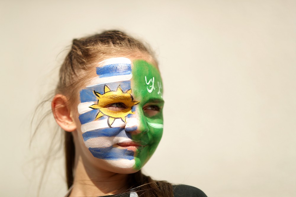 自国国旗をペインティングして戦況を見つめるウルグアイサポーターの少女（ゲッティ）