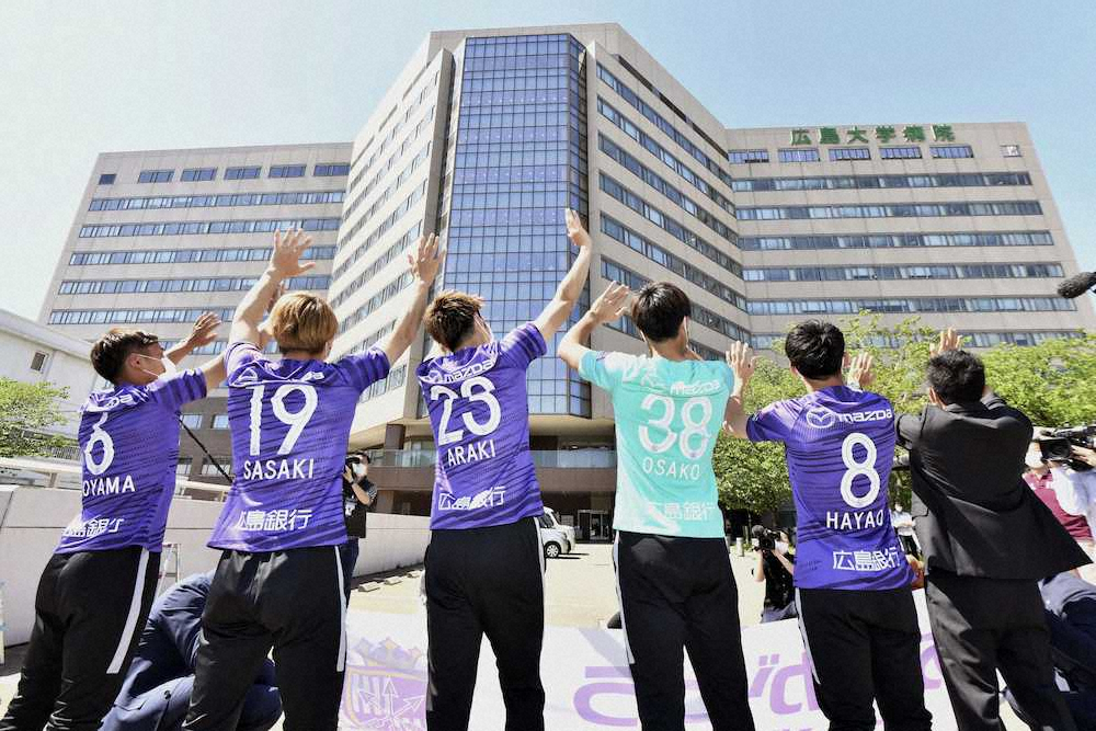 広島大学病院を訪問し、病棟に向かって手を振る広島の選手ら