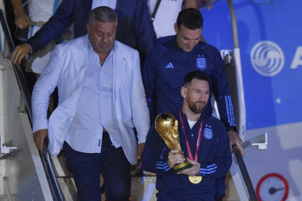 現地時間の20日早朝、アルゼンチンのブエノスアイレスで FIFAワールドカップのトロフィーを持って飛行機から降りるメッシ（AP）