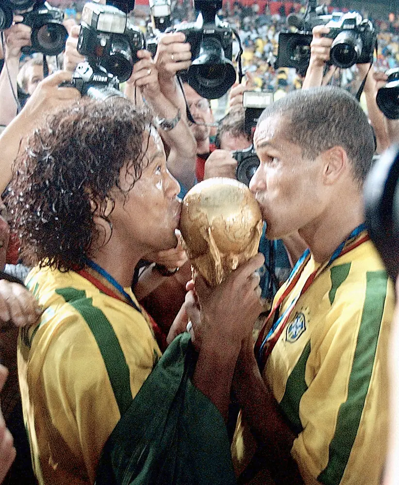 02年Ｗ杯日韓大会で優勝を飾り、トロフィーにキスするブラジル代表ロナウジーニョ（左）とリバウド（AP）