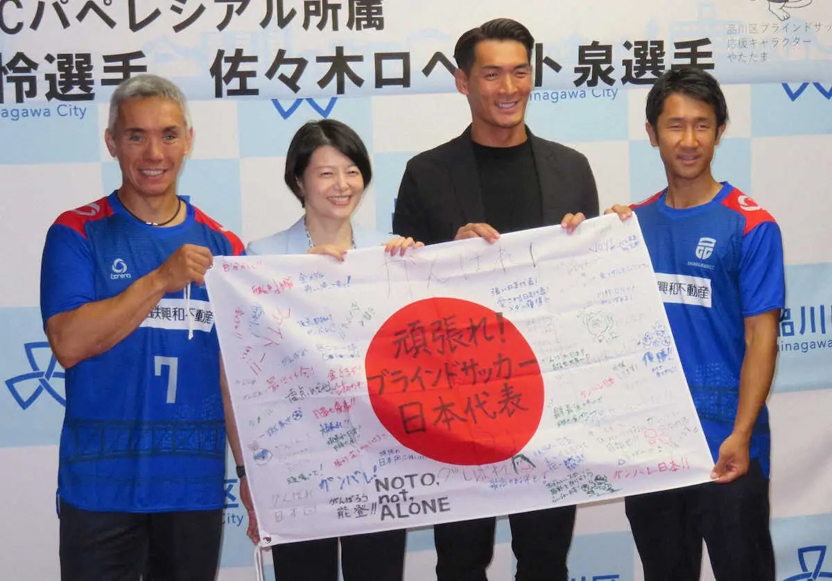 激励メッセージ入りの日の丸を広げる（左から）佐々木、森沢区長、槙野氏、川村