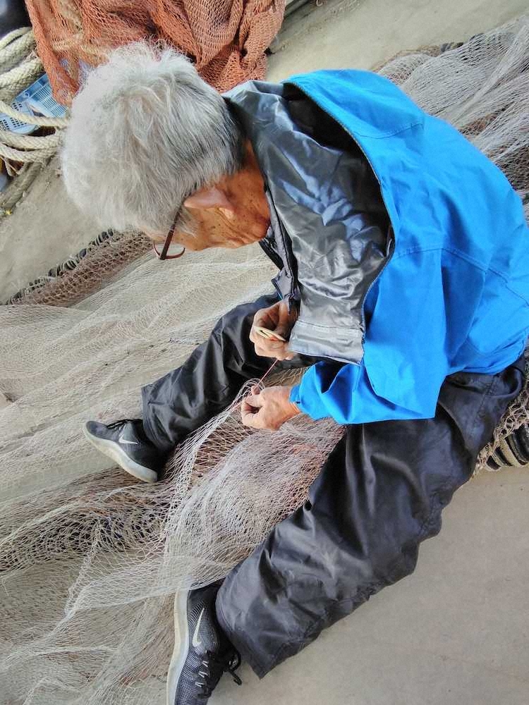 川嶋　澪翔「漁に行くための準備」これは漁師さんが漁に行く前日に網を修理しているところです。白い網を別の赤いひもにからめて結びます。三角形の道具を網の四角形のところに赤い糸をひっかけて修理していました。