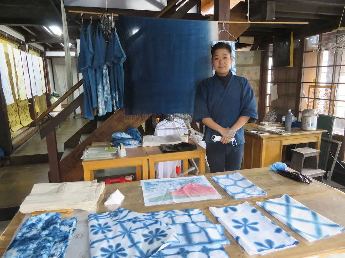 ストールやTシャツ、手ぬぐいなど藍染の作品に包まれる山崎杜人さん