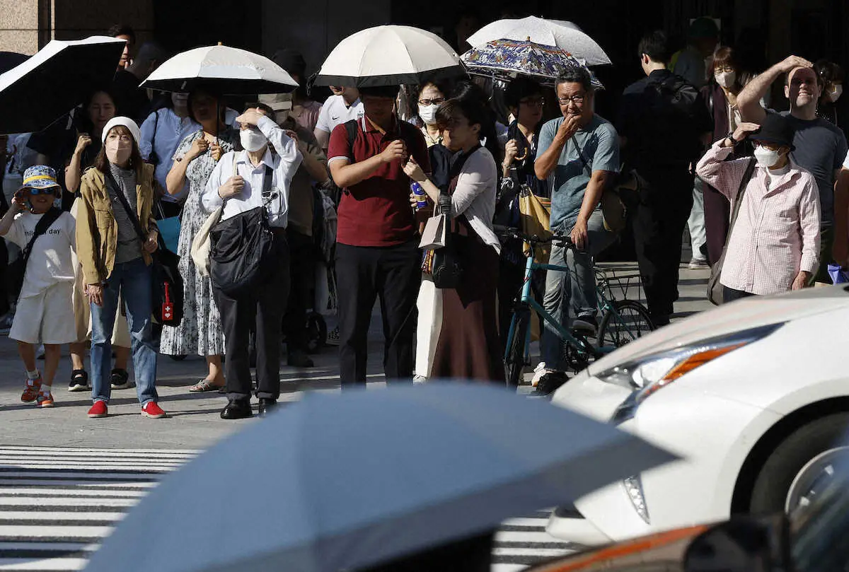 気温が上がり、東京・銀座で日傘を差して信号を待つ人たち＝14日午後
