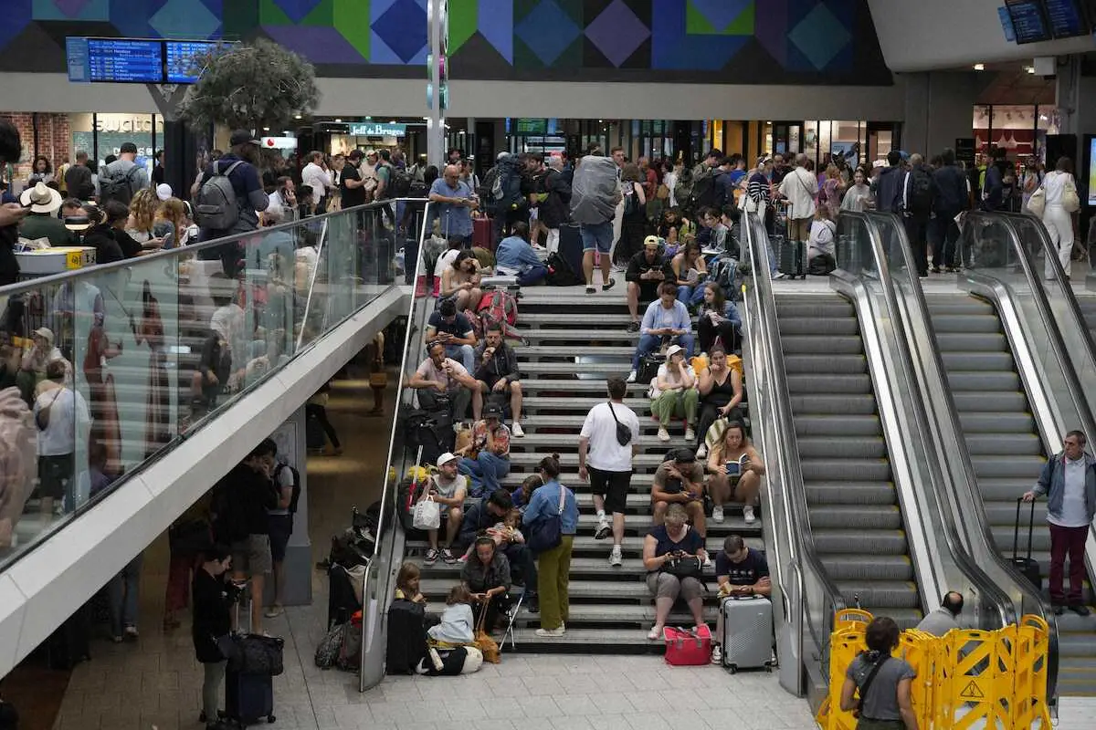 破壊行為を受けて高速列車網が遅延し、モンパルナス駅の階段に座り込む旅行者ら＝26日、パリ（AP）